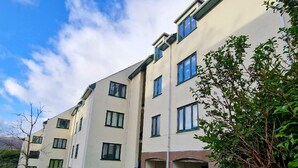 A multi-story residential building with a flat facade, multiple windows, and a small entrance area. - Bowness Hideaway (Windermere)