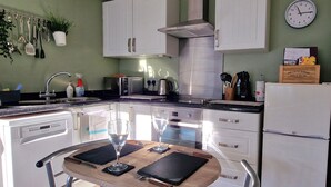 A modern kitchen with white cabinets, a stainless steel range hood, a microwave, and a refrigerator. - Bowness Hideaway (Windermere)