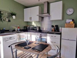 Una cocina moderna con armarios blancos, una campana extractora de acero inoxidable, un microondas y un refrigerador.
