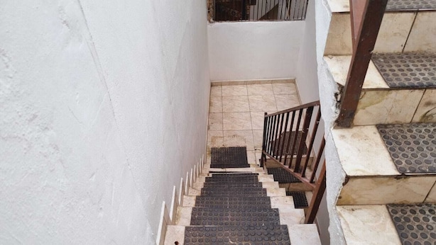 Una escalera con barandillas metálicas y pavimentación táctil en la parte inferior.