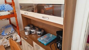 Una kitchenette compacta con encimera de madera, horno integrado y cafetera.
