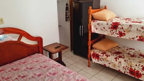 Una habitación con una cama litera, un guardarropa de madera y una mesita con un control remoto.