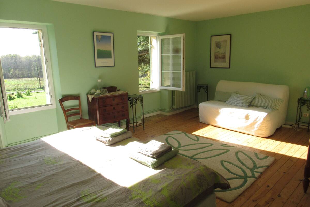 A bedroom with a bed, a dresser, a chair, a window, and a radiator.