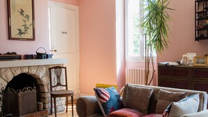 A cozy living room with a fireplace, a sofa, a coffee table, and a bookshelf. - La Ferme du Ciel (Laruscade)