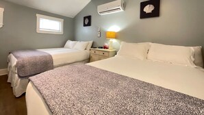 Una camera da letto con due letti, un comodino con una lampada e un condizionatore d'aria.