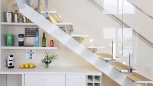 Une cuisine moderne dotée d’un escalier intégré, de meubles blancs et de divers accessoires de cuisine.