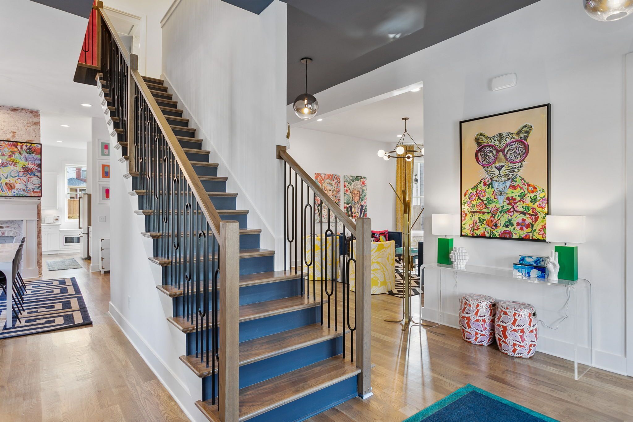 A modern interior with a wooden staircase, a dining area, and a living space with a colorful abstract painting.