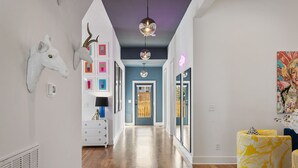 A hallway with a wooden floor, a white dresser, a mirror, and a door leading to another room.