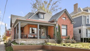 A two-story house with a stone foundation, a brick exterior, and a grey roof.