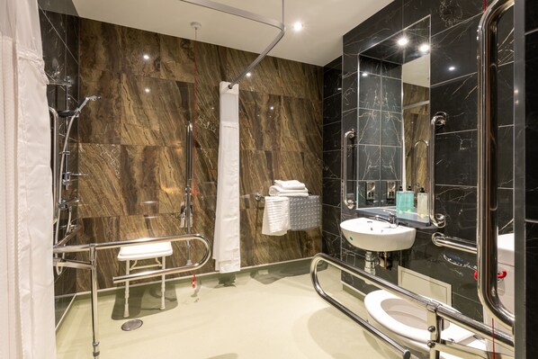 Un baño moderno con cabina de ducha de vidrio, un lavabo blanco y un espejo grande.