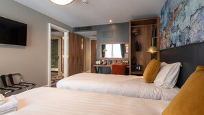 A hotel room with two beds, a TV, a desk, and a bathroom visible through an open door. - Keavans Port (Dublin)