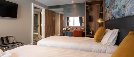 A hotel room with two beds, a TV, a desk, and a bathroom visible through an open door.