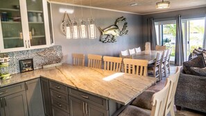 Une cuisine spacieuse avec un grand îlot central, des chaises en bois et un coin repas agrémenté d’un canapé.