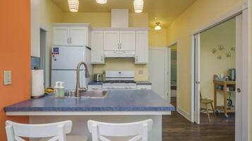 A kitchen with white cabinets, a blue countertop, and a central island with two white chairs.