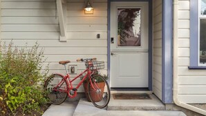 A red bicycle parked outside a house with a white door and a small porch. - #StayInMyDistrict Lake Oswego Honey Bee Cottage (Lake Oswego)
