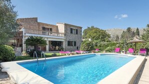 A rectangular swimming pool with a clear blue water, surrounded by a white pool deck. There are pink lounge chairs and a thatched umbrella on the right side. - Finca Can Tomeu, private pool, wifi, 4 bedrooms, 10 minutes to the beach  (Pollenca)