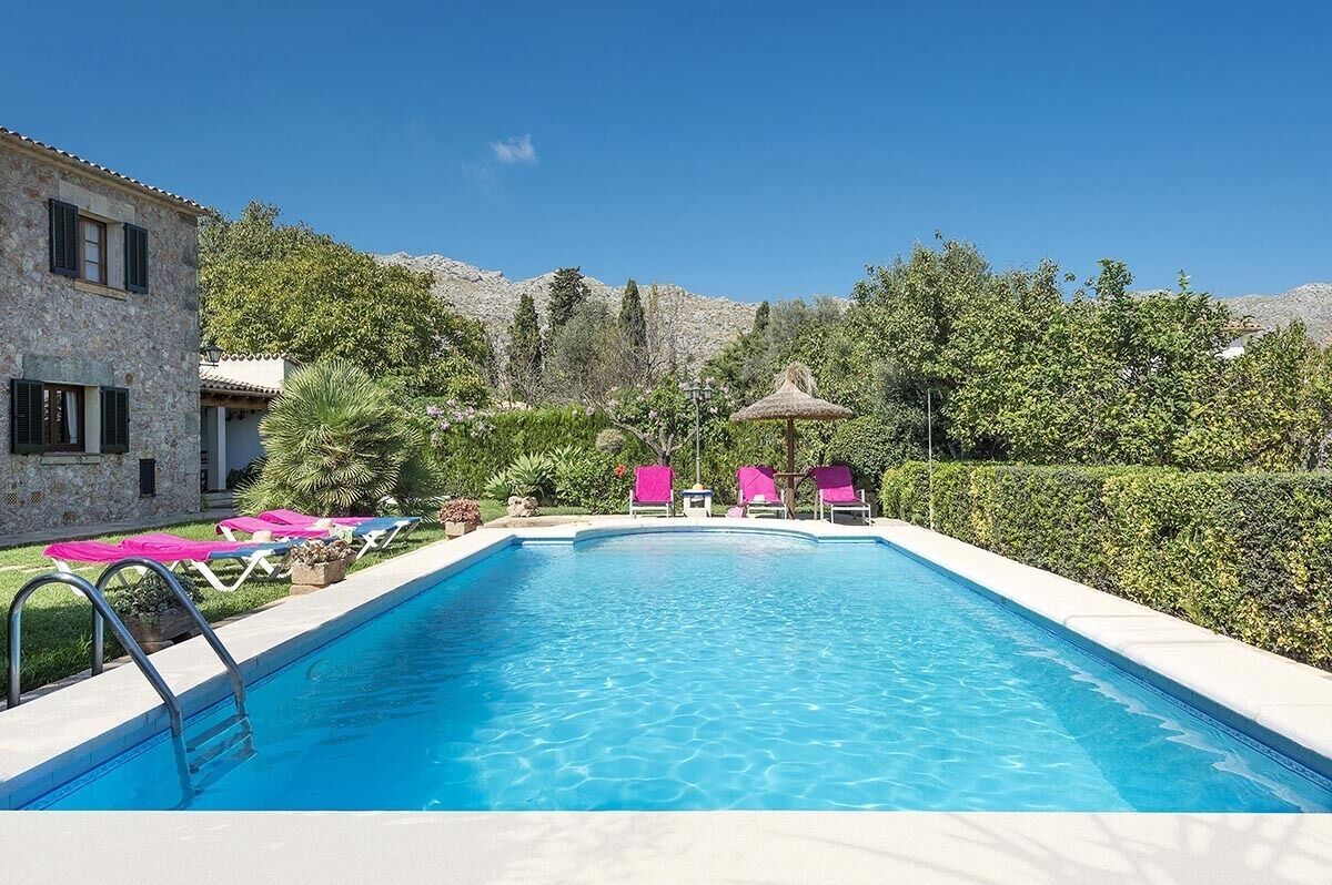 A swimming pool with lounge chairs and a building with stone walls.