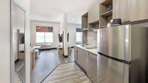 A modern kitchen with stainless steel appliances, wooden cabinets, and a herringbone-patterned floor. - Best Western Plus Executive Residency Carlsbad Hotel (Carlsbad)