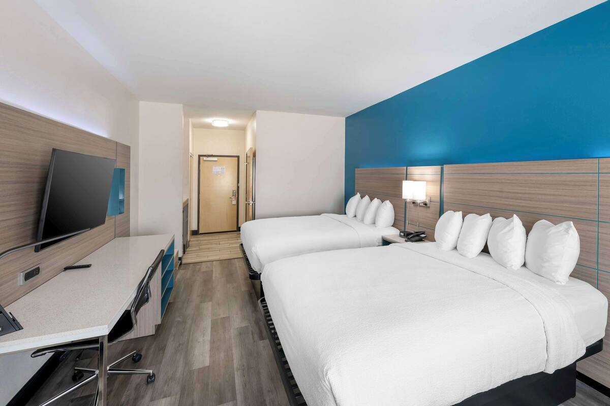 Ein Hotelzimmer mit zwei Betten, einem Schreibtisch und einem Fernseher.