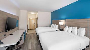 A hotel room with two beds, a desk, and a television.