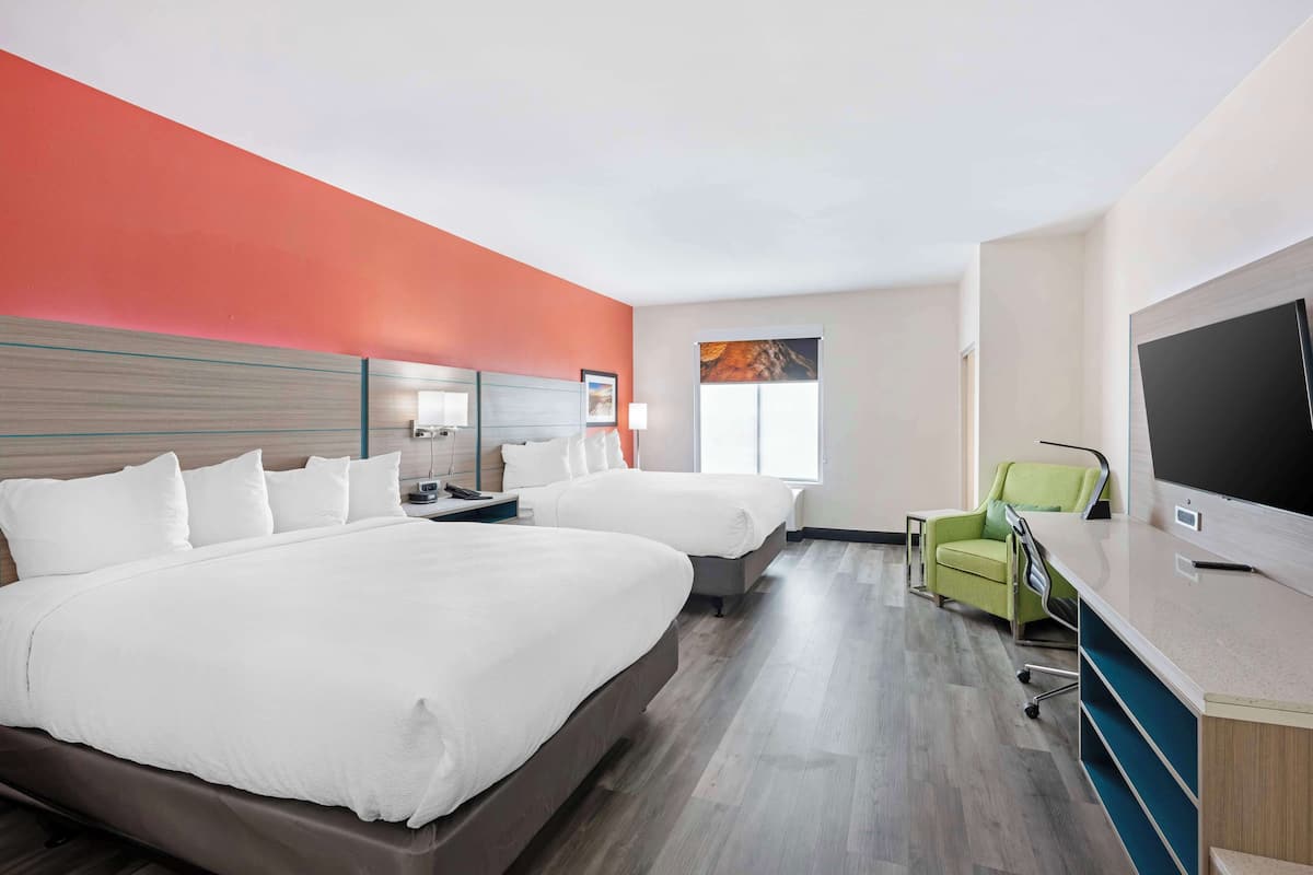 Ein Hotelzimmer mit zwei Betten, einem Schreibtisch, einem Stuhl und einem Fernseher.