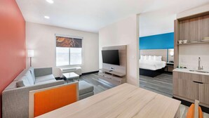 A modern hotel room with a sofa, a dining table, a TV, a bed, and a kitchenette. - Best Western Plus Executive Residency Carlsbad Hotel (Carlsbad)