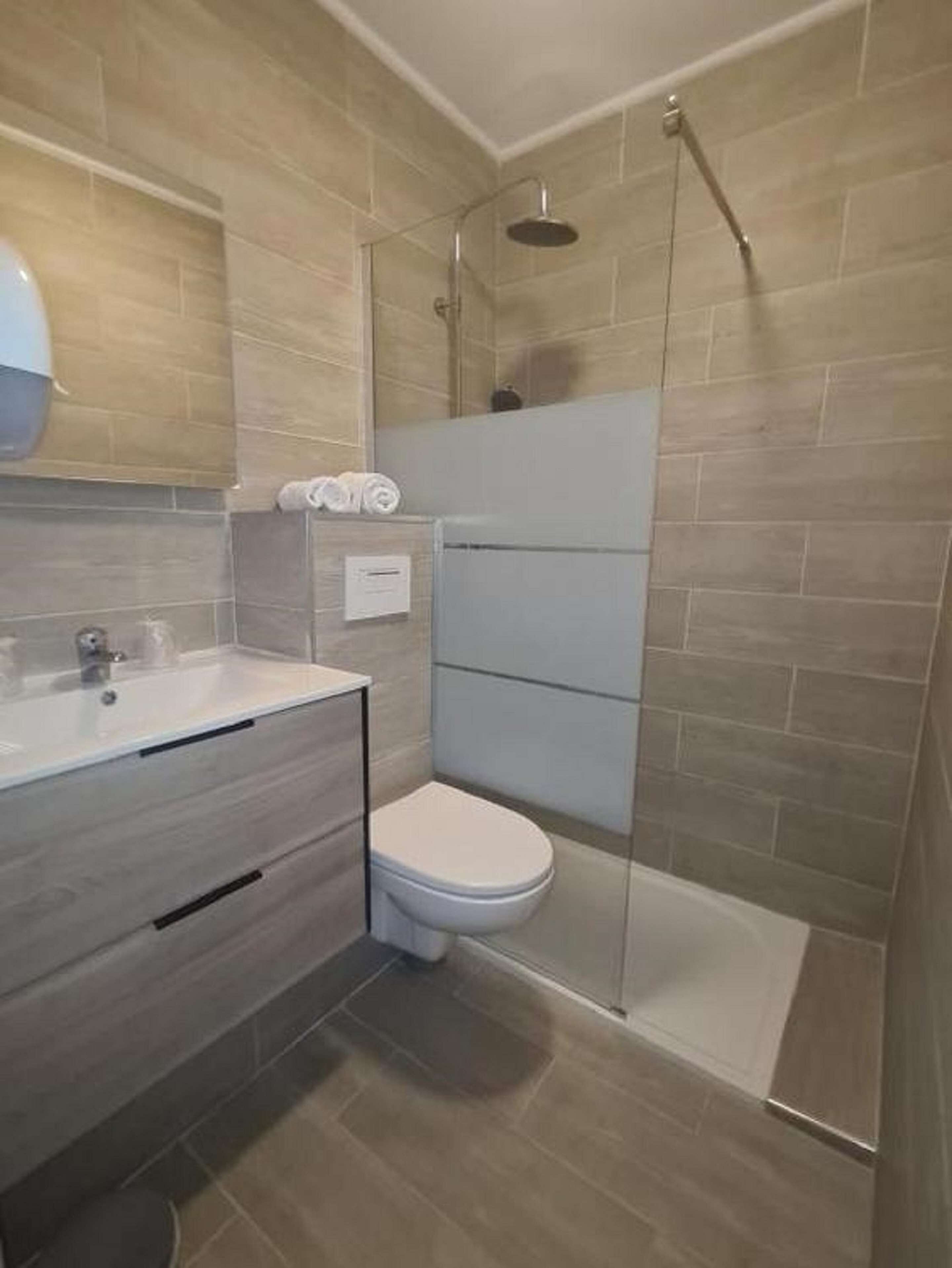 A modern bathroom with a shower, toilet, and sink.