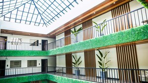 Un atrium à plusieurs niveaux doté d’un plafond en verre, d’une pelouse artificielle verdoyante et de lambris en bois.