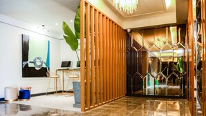 Un hall d’entrée moderne avec une cloison en bois, un bureau avec un ordinateur portable et une grande plante.