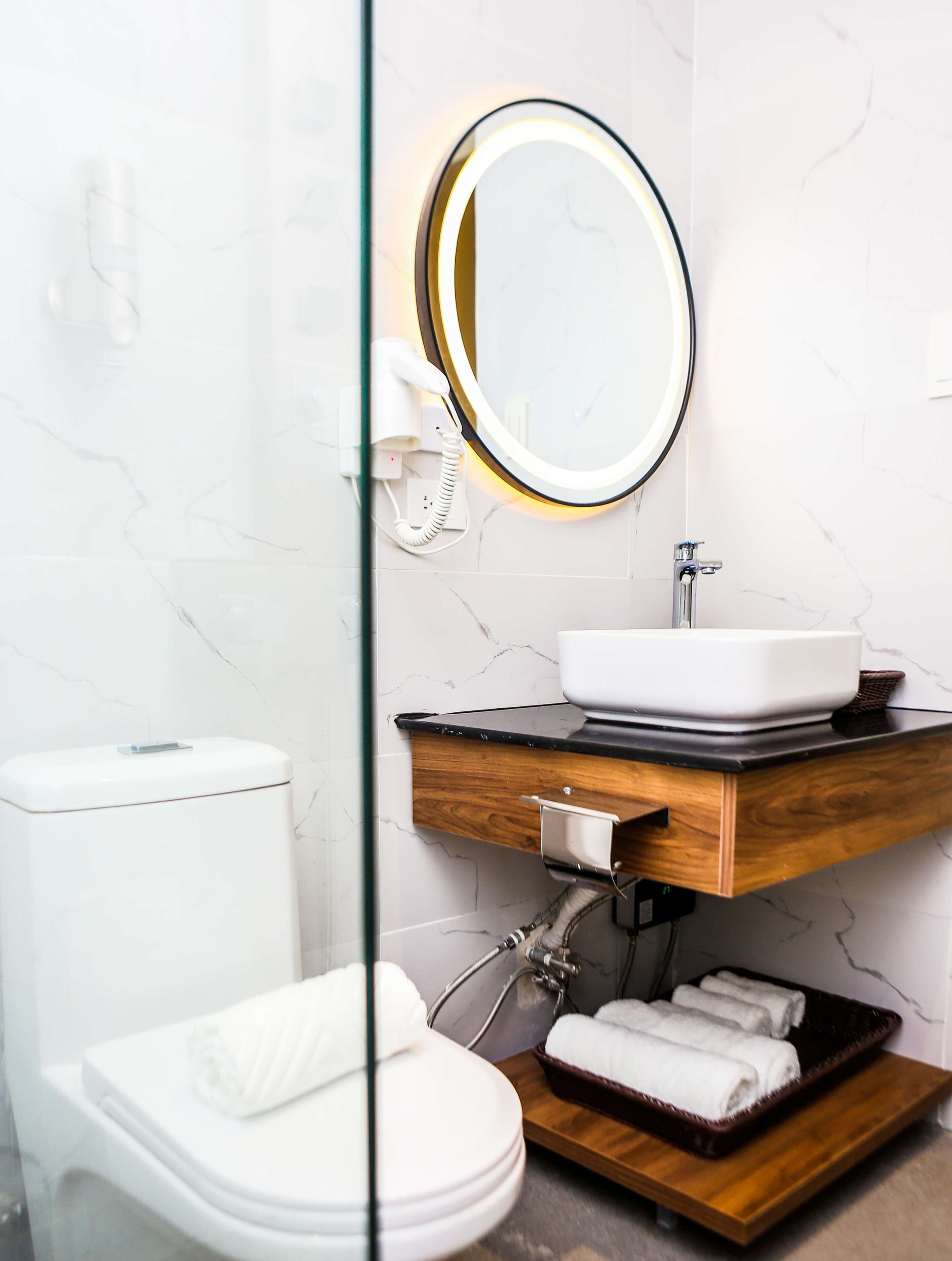 A modern bathroom with a toilet, sink, and mirror.