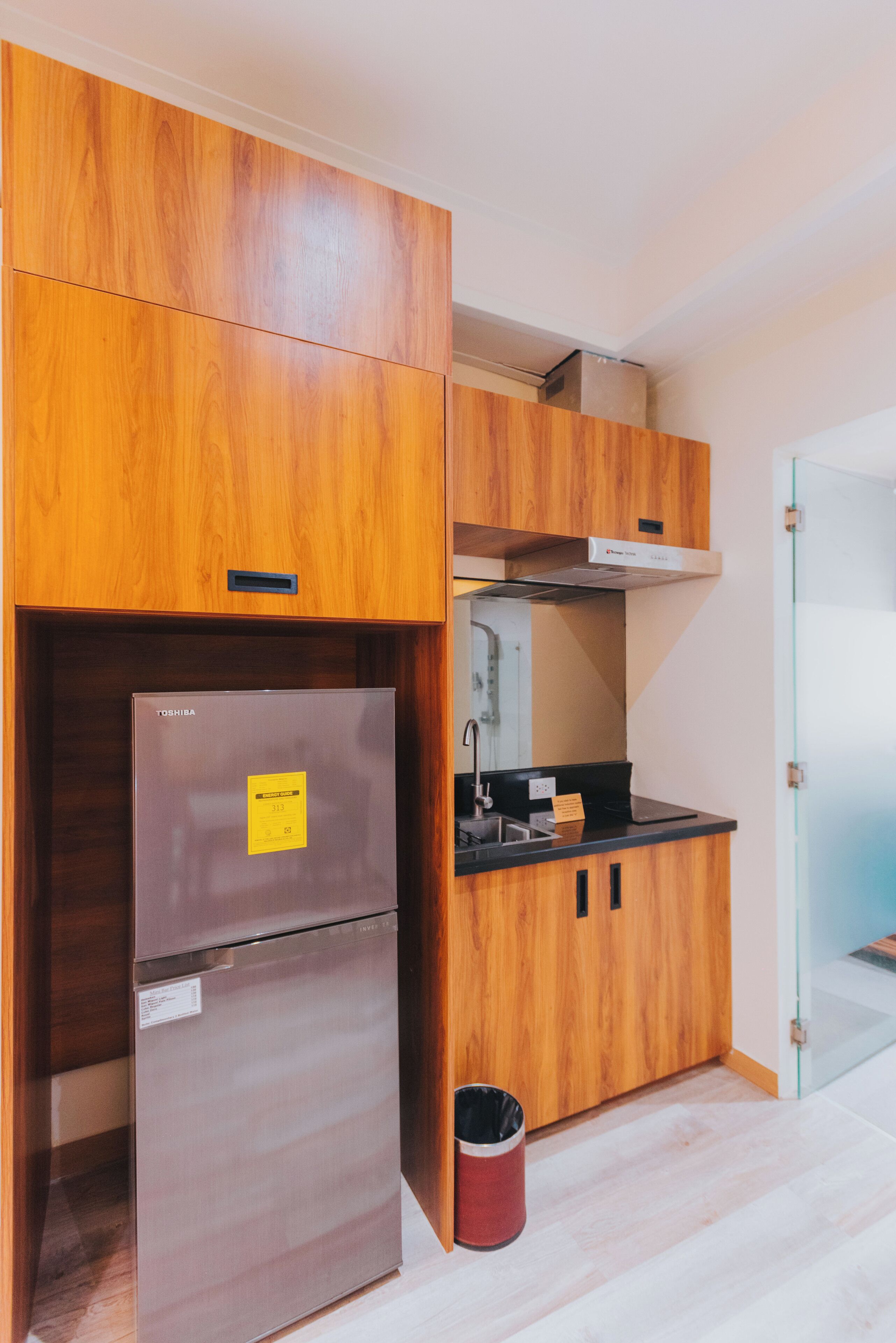 Eine kleine Küche mit Holzschränken, einem Edelstahlkühlschrank und einer Arbeitsplatte.