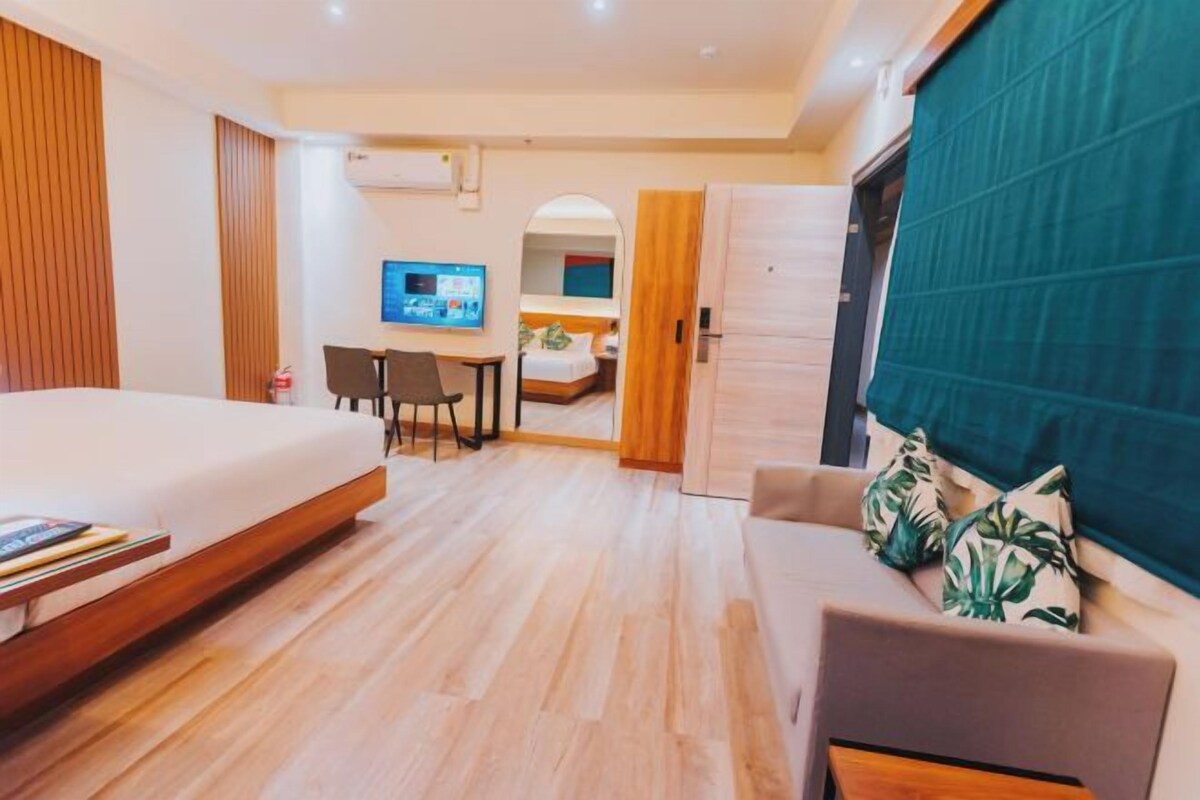Una habitación de hotel con una cama, un escritorio con computadora, un sofá y un televisor.