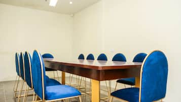 A conference room with a rectangular table and blue upholstered chairs with gold frames.