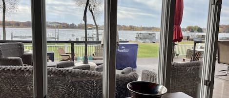 A room with a view of a lake, wicker furniture, and a table with a bowl.