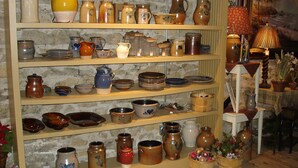 Une exposition de poteries et de céramiques présentées sur des étagères.