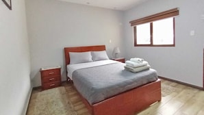 A bedroom with a bed, bedside tables, a window, and a carpeted floor. - Welcome to your home in Baños (Baños de Agua Santa)