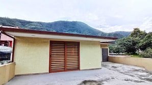 A building with a red roof, a large wooden door, and a small attached structure. - Welcome to your home in Baños (Baños de Agua Santa)
