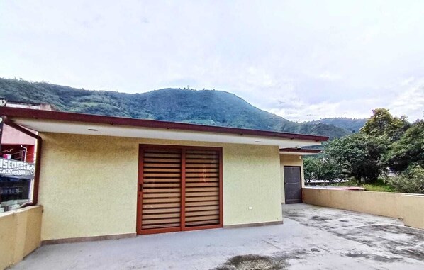 Un bâtiment avec un toit rouge, une grande porte en bois et une petite structure attenante.