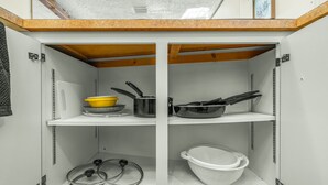 A kitchen with white cabinets, a wooden countertop, and various kitchen utensils and appliances.