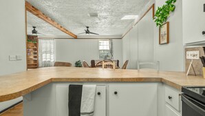 A kitchen with a curved countertop, a ceiling fan, and a dining area with chairs and a table.