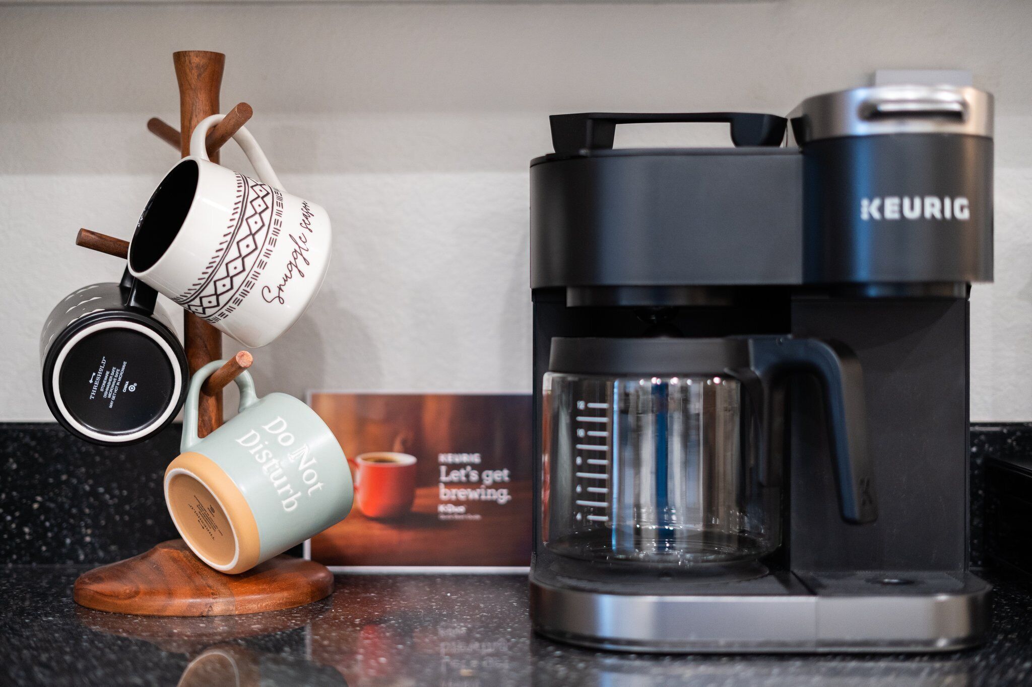 A coffee maker and two mugs on a countertop.