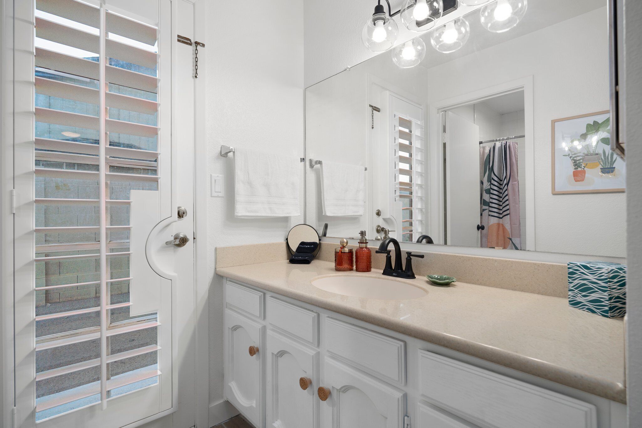 A bathroom with a white vanity, a large mirror, and a shower area.
