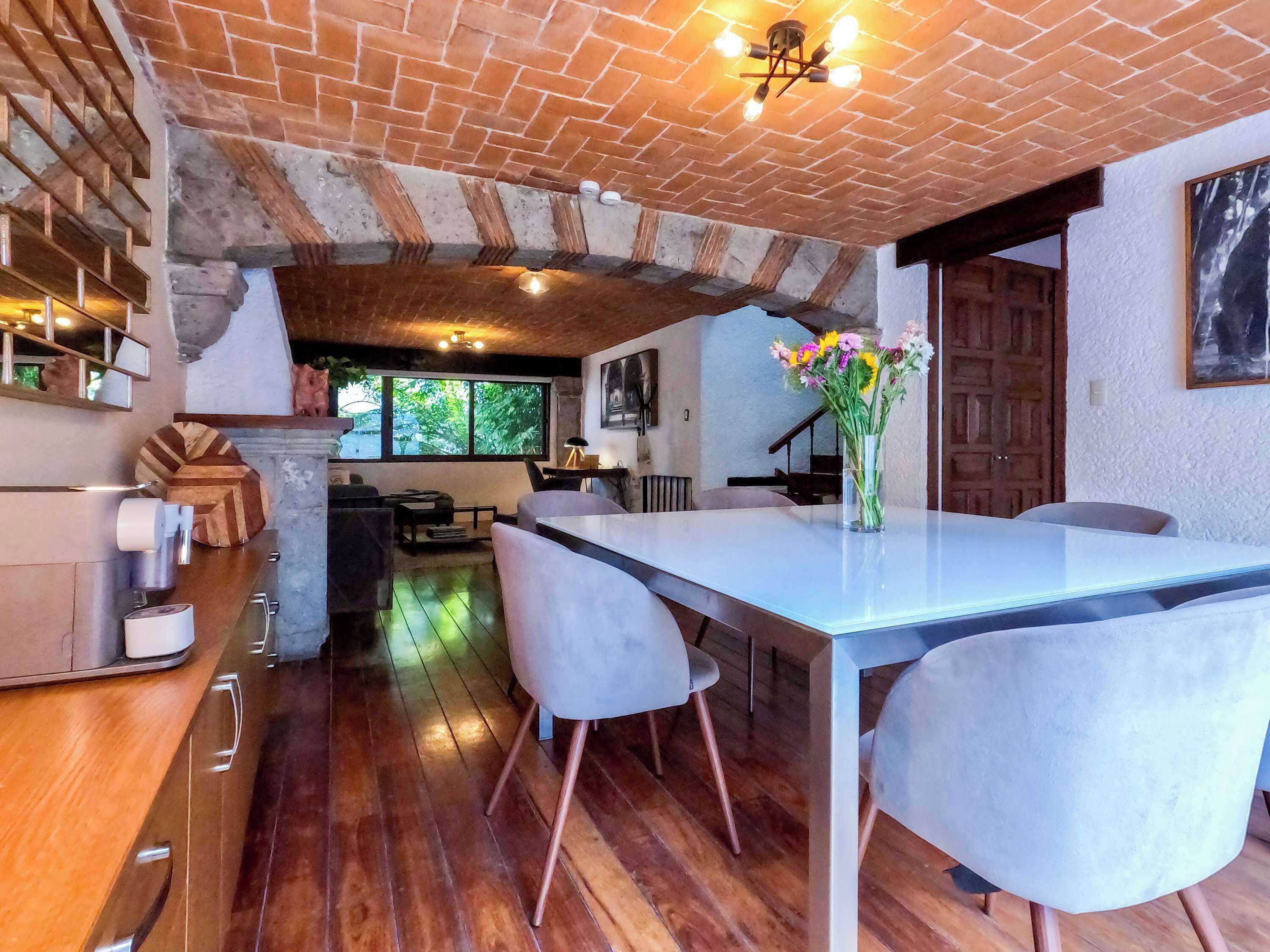 A rustic kitchen with exposed brick walls, a wooden dining table, and modern chairs.