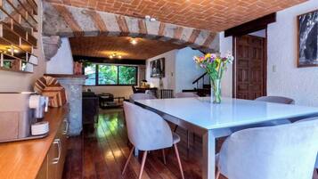 A rustic kitchen with exposed brick walls, a wooden dining table, and modern chairs.