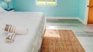 A bedroom with a bed, a ceiling fan, a window, and a door. - In the heart of Stuart-close to beaches (Stuart)