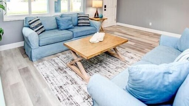 A modern living room with a blue sofa, a wooden coffee table, and a ceiling fan. - In the heart of Stuart-close to beaches (Stuart)