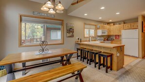 Una cocina con armarios de madera, una isla central con taburetes, un microondas y un refrigerador.