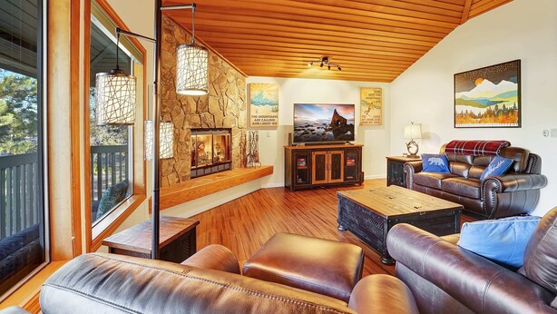 Ein gemütliches Wohnzimmer mit Ledersofas, einem Kamin aus Stein und einem Fernseher.