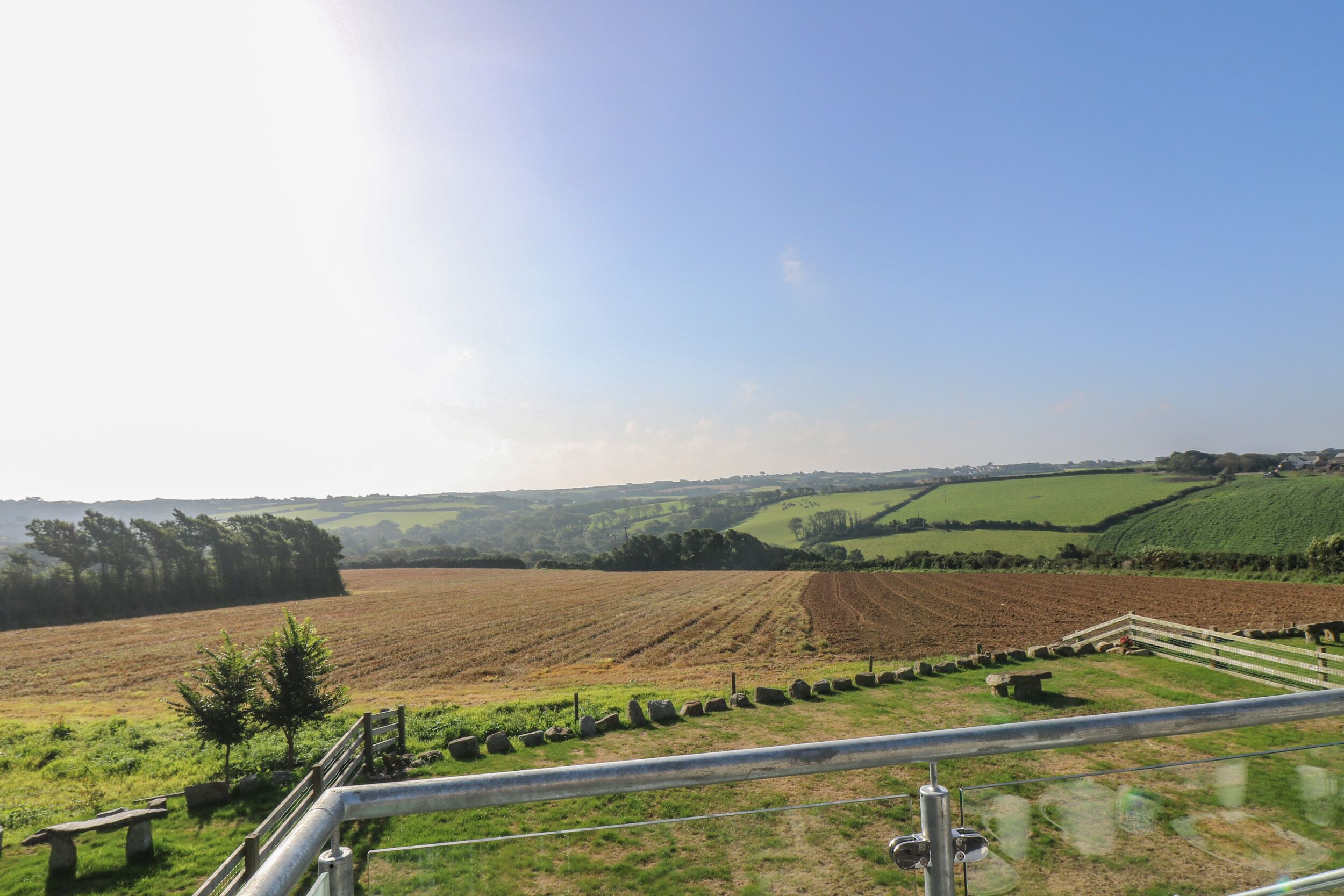 A rural landscape with fields, a fence, and a bench.