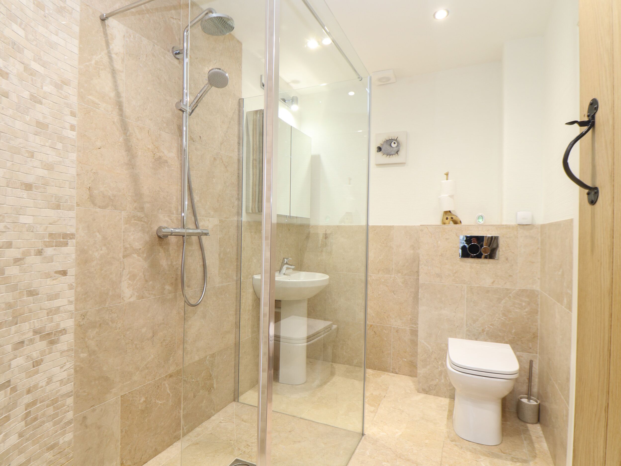 A modern bathroom with a glass-enclosed shower, a white sink, and a toilet.